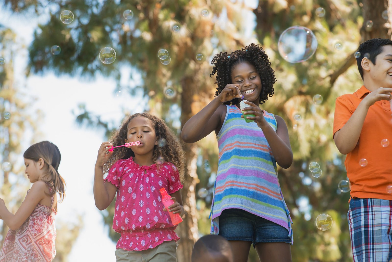 Group of children laughing and blowing bubbles.